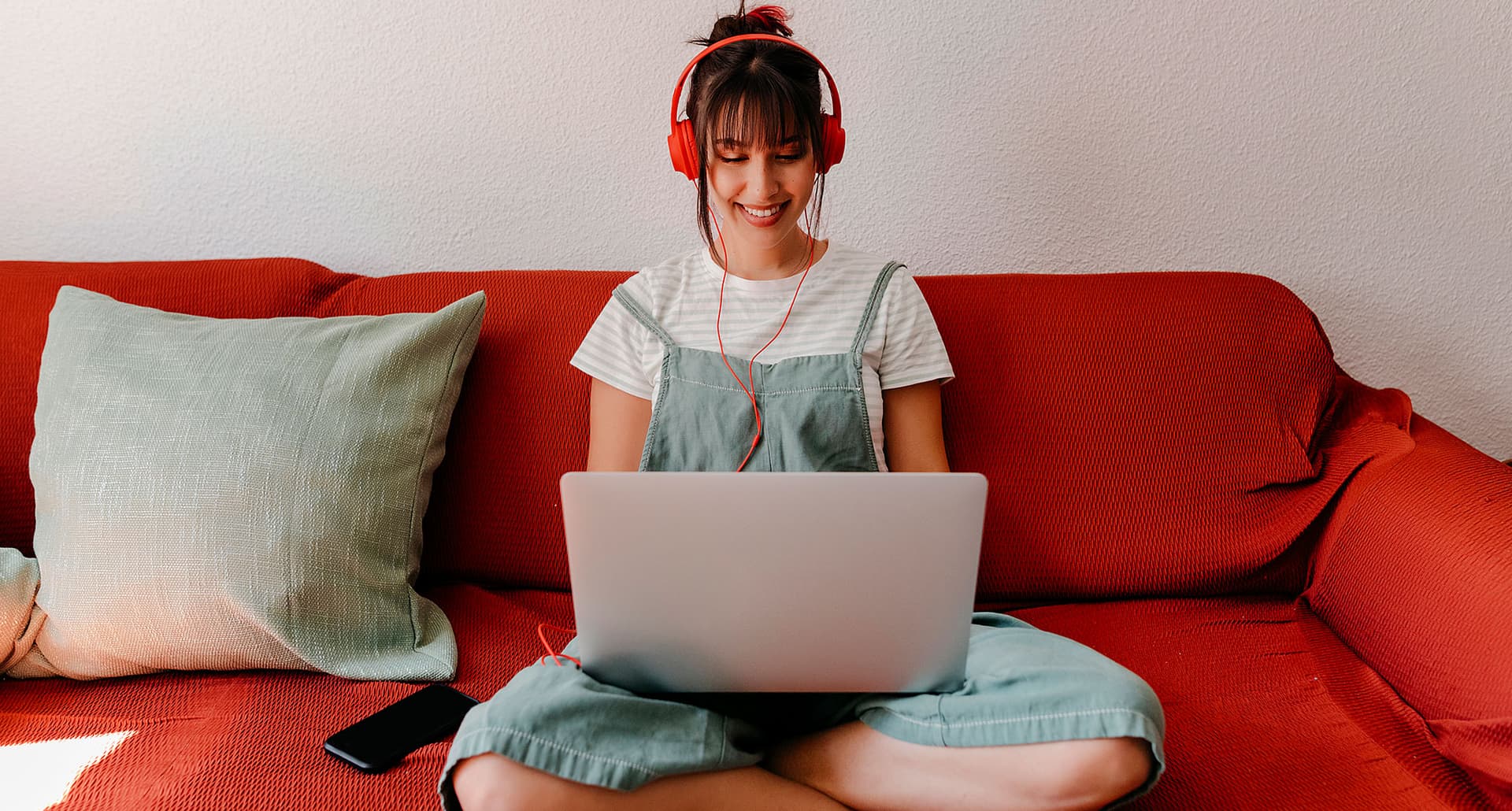 colors that go with red: woman sitting cross-legged on a red couch on a laptop