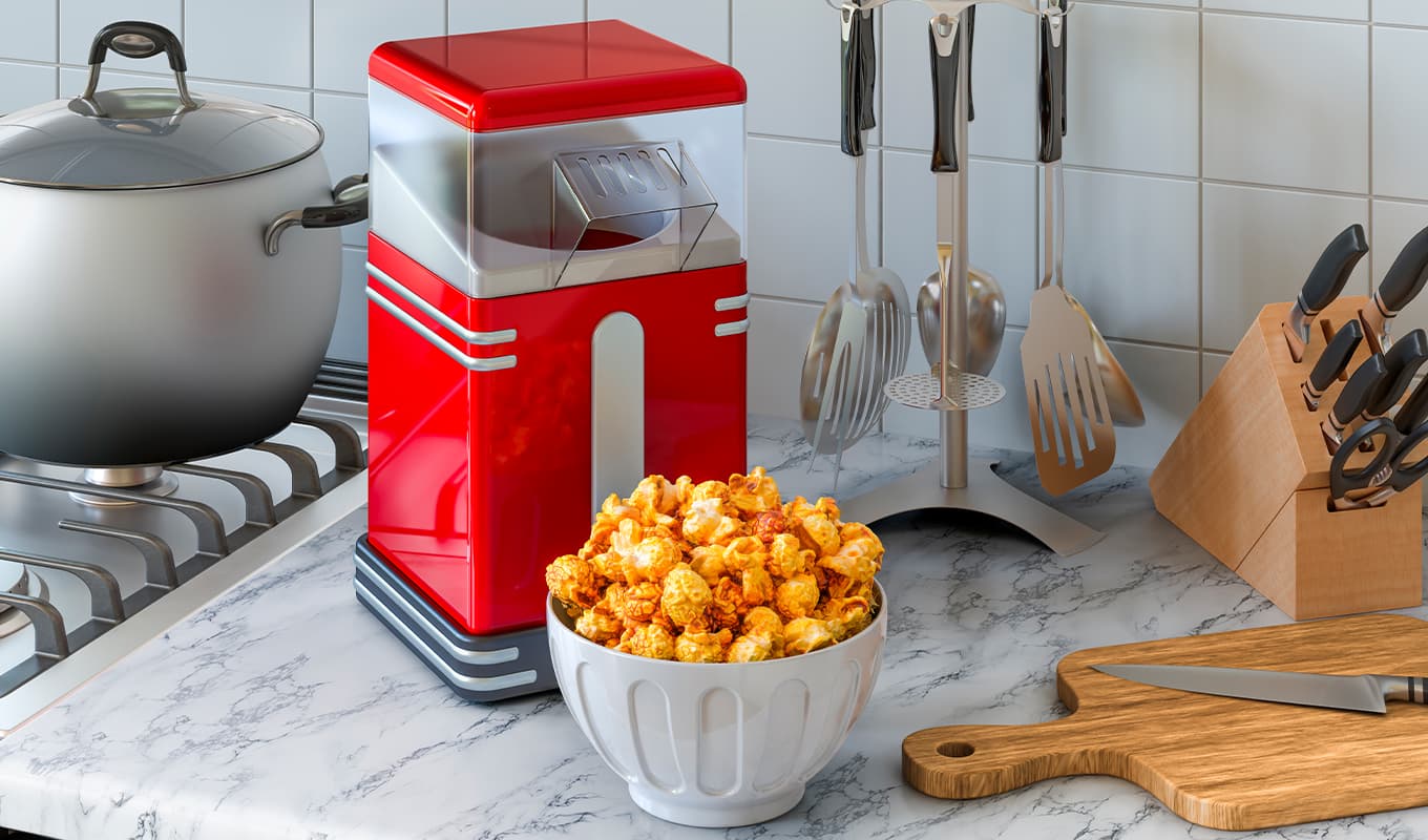 Best popcorn maker: A popcorn maker on a marble countertop with a bowl of cheese popcorn