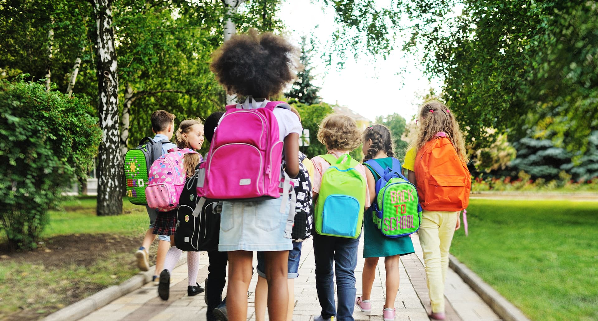 back to school quotes: group of elementary school children walking on the sidewalk with their backpacks