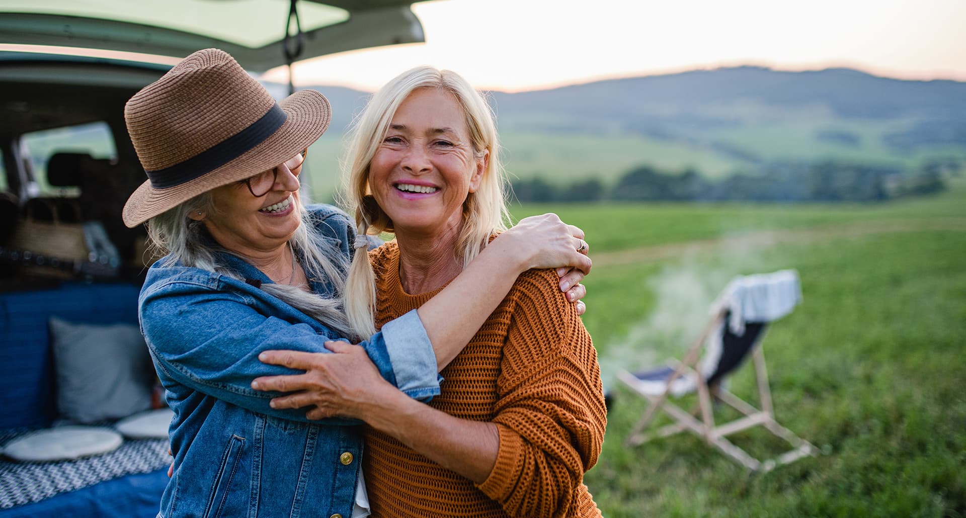 Two women embrace while laughing as they set up for an outdoor adventure.