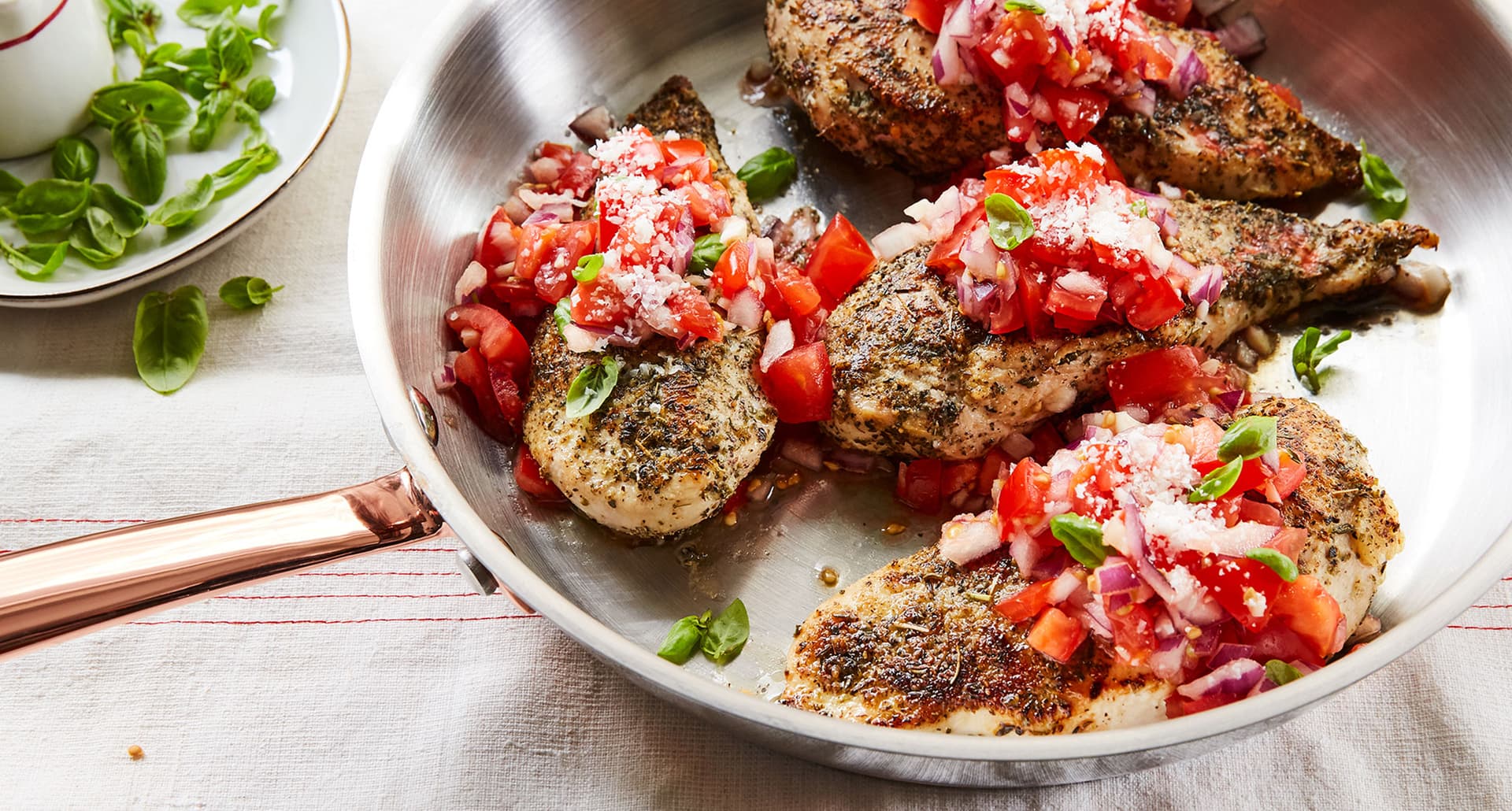keto chicken recipes: bruschetta chicken in a skillet topped with tomatoes