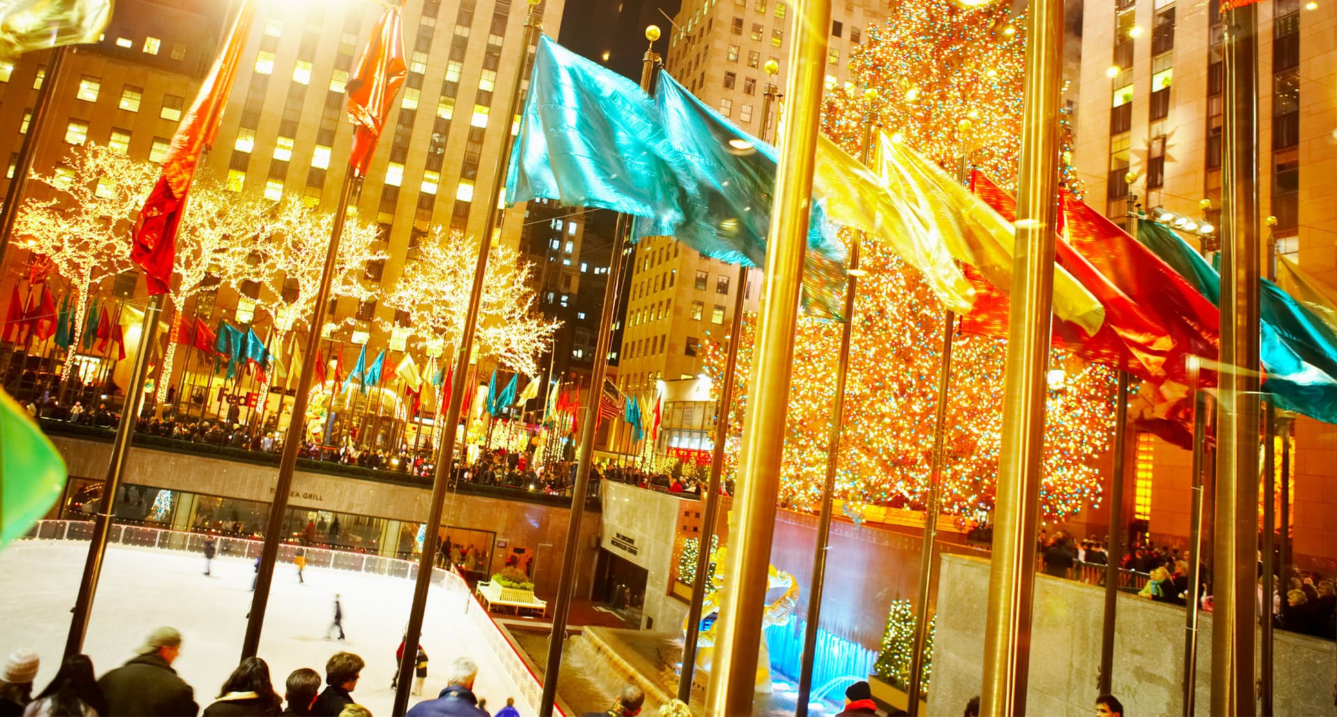 Best Places to Ice Skate in NYC - A yellow toned photograph of the flags, ice skating rink, and Christmas Tree at Rockefeller Center.