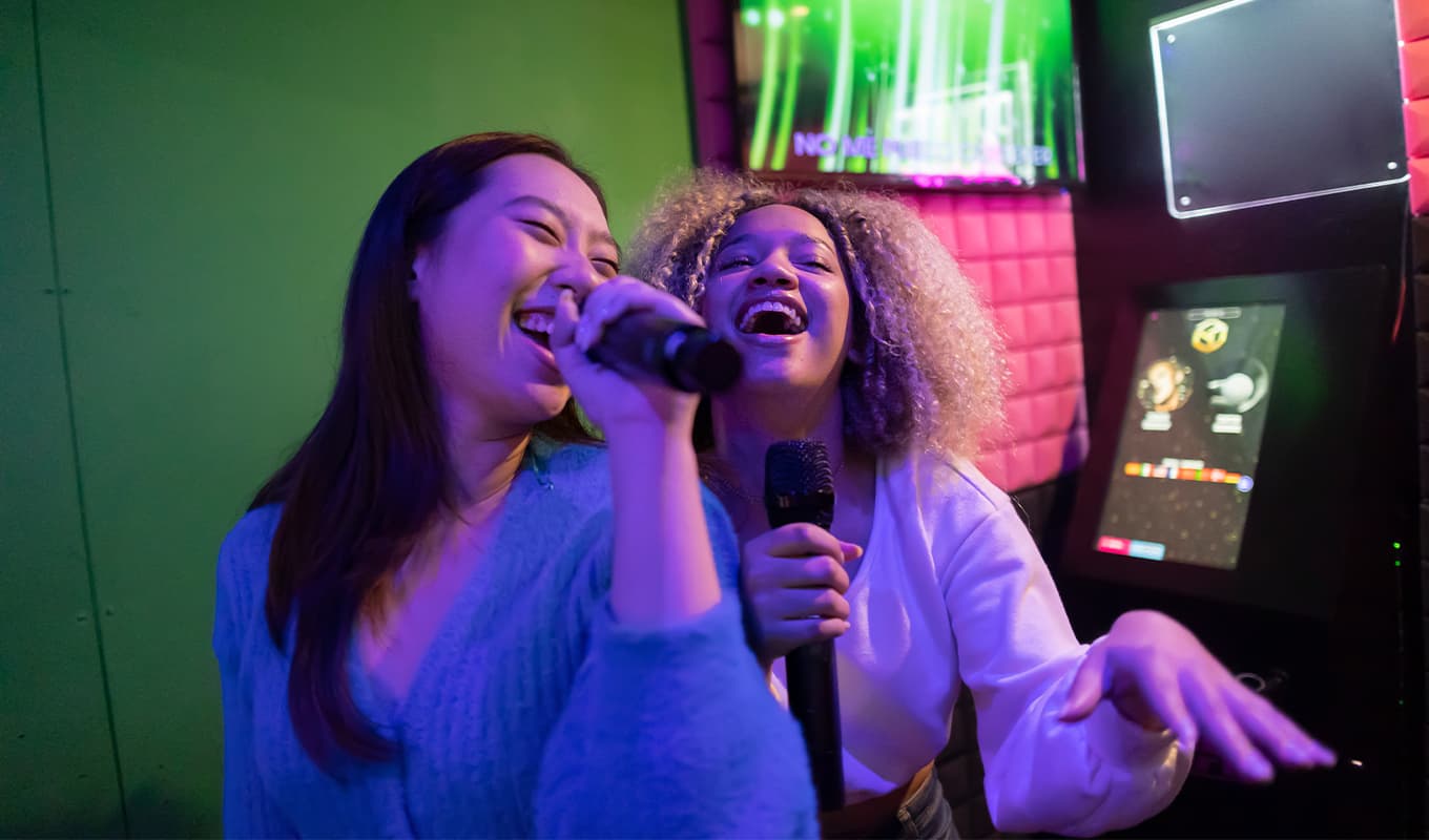 karaoke songs: two friends sing together in a dark room