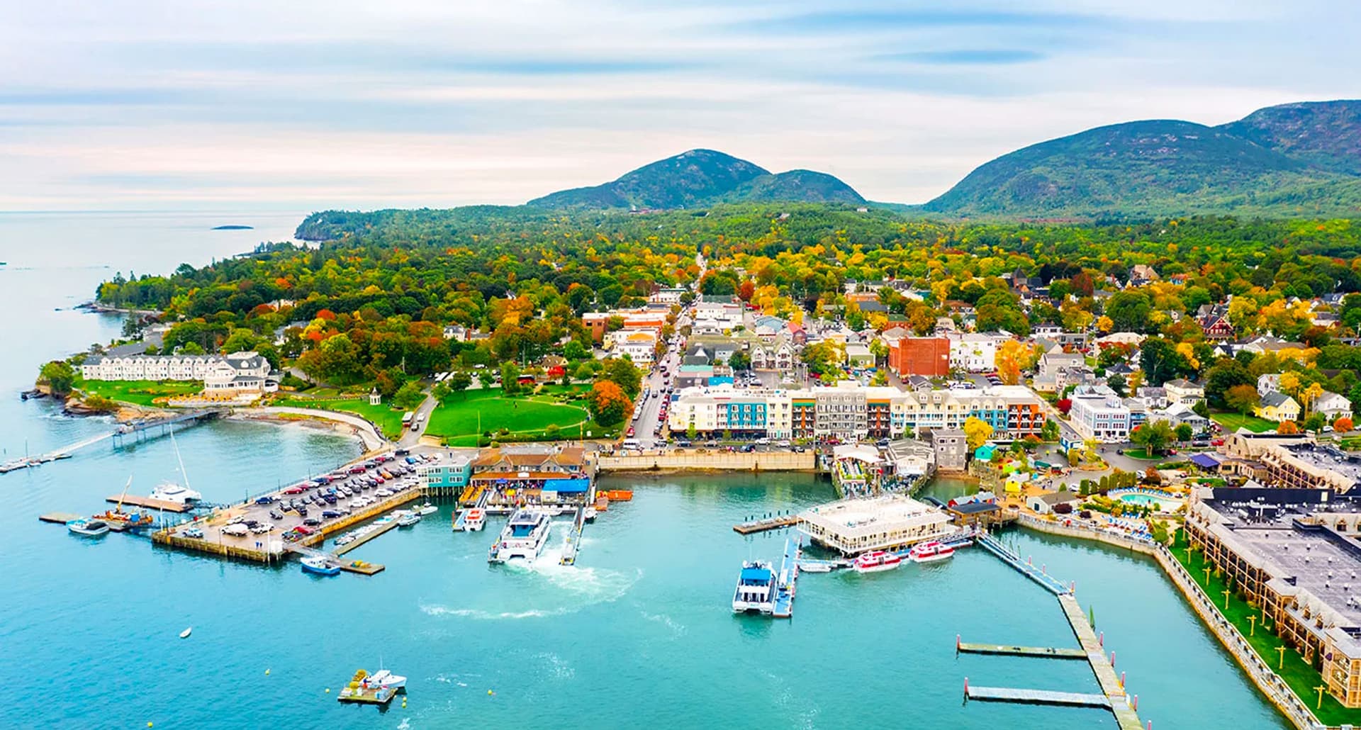 Places Like the Hamptons - An overhead shot of an inlet at Bar Harbor in Maine. There are boats, docks and colorful houses on the shore. The water is clear and the sky is bright.