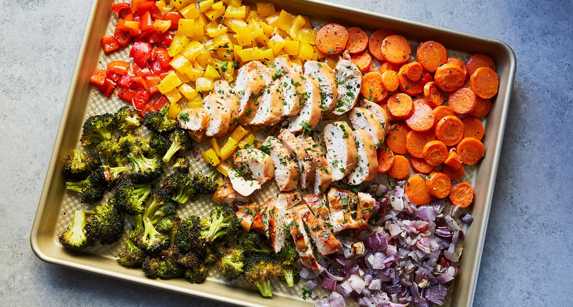 keto dinner recipes: sliced chicken breast on a sheet pan surrounded by broccoli, red onion, carrots and bell peppers