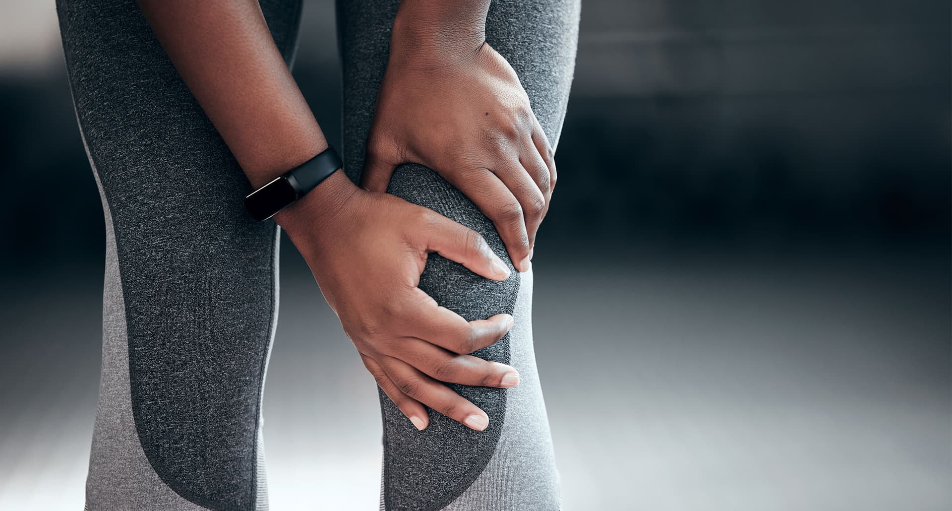 young woman experiencing pain in her knee at the gym