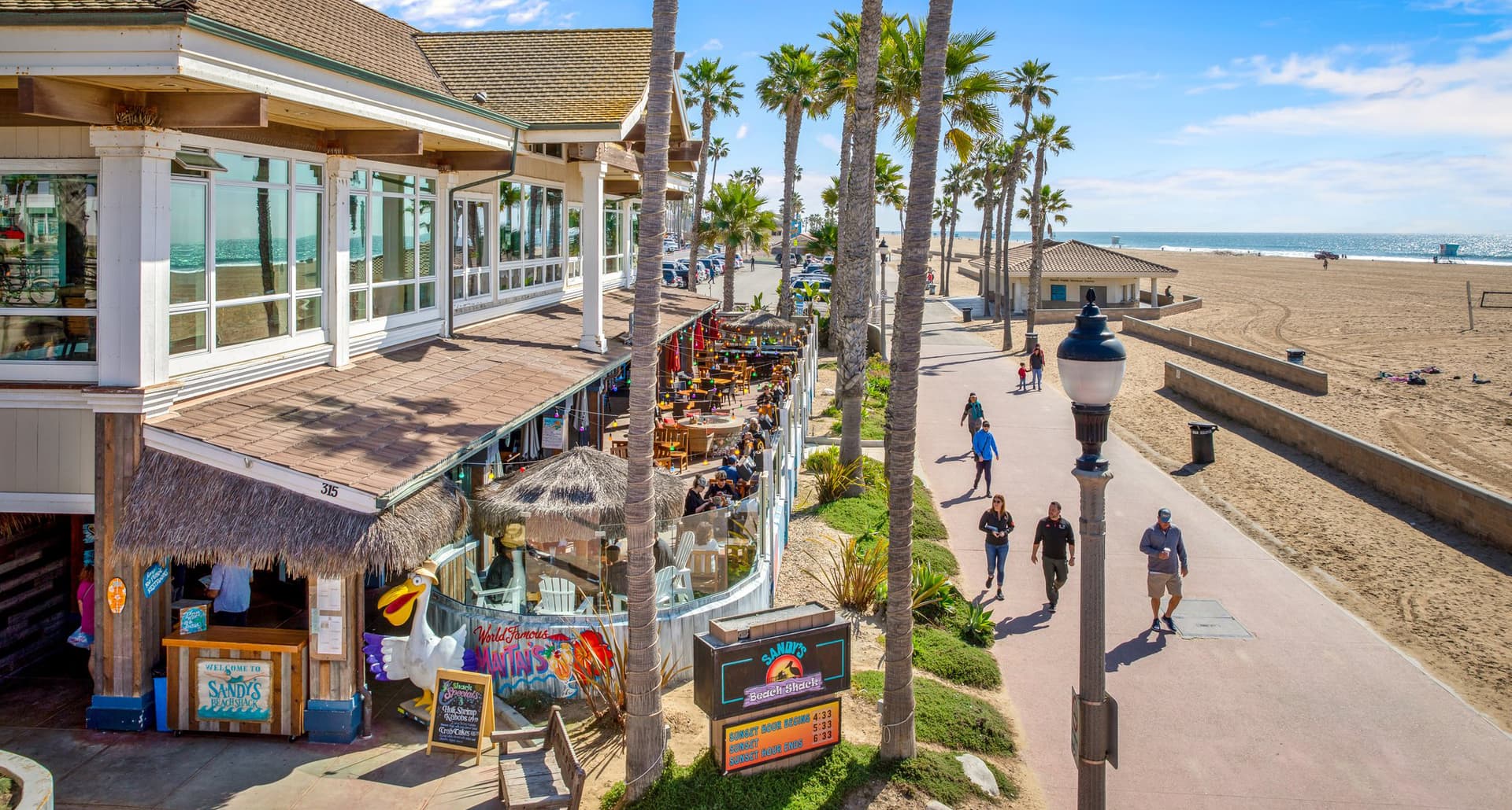 huntington-beach: A photo of the shoreline strip in Huntington Beach. It's bustling with people, shops and restaurants.