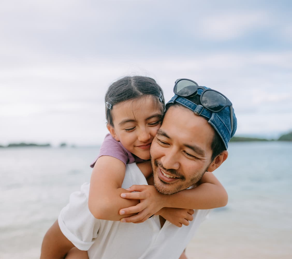 father's day quotes: asian dad piggy backing his daughter on the beach