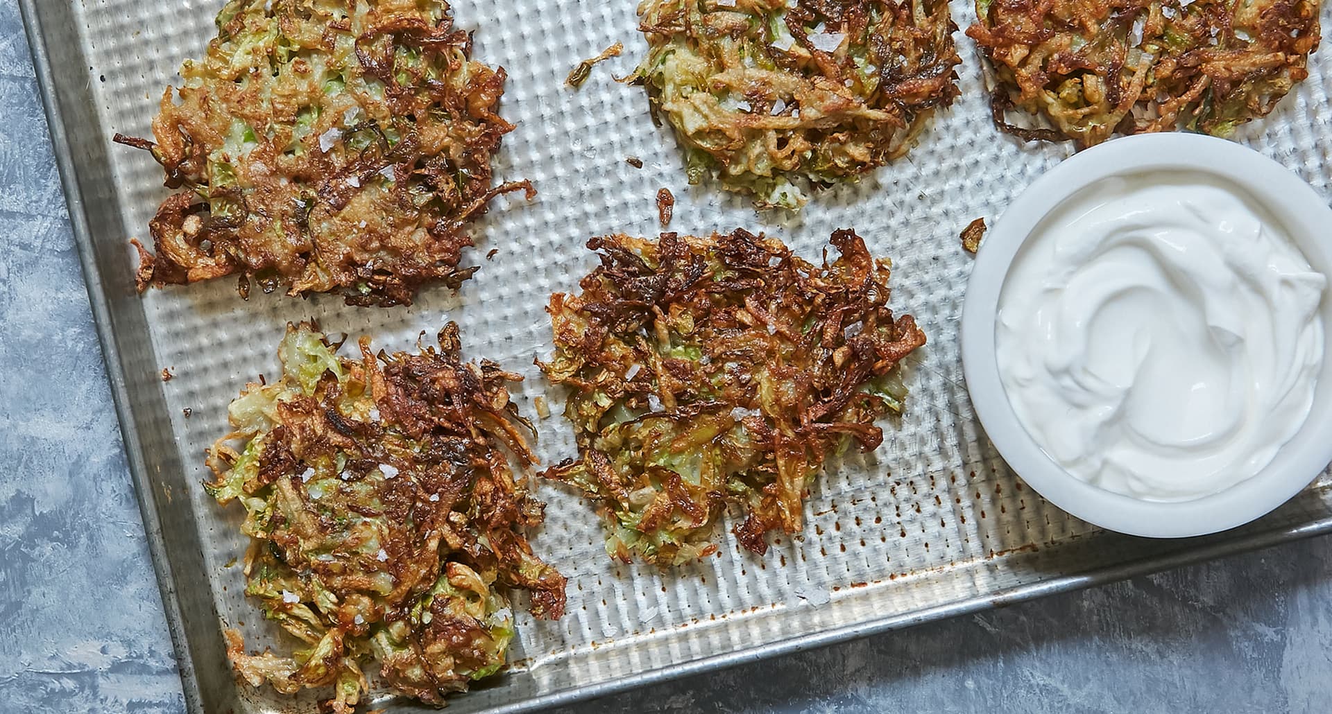 dairy-free thanksgiving sides: brussels sprout latkes on a sheet pan with sour cream