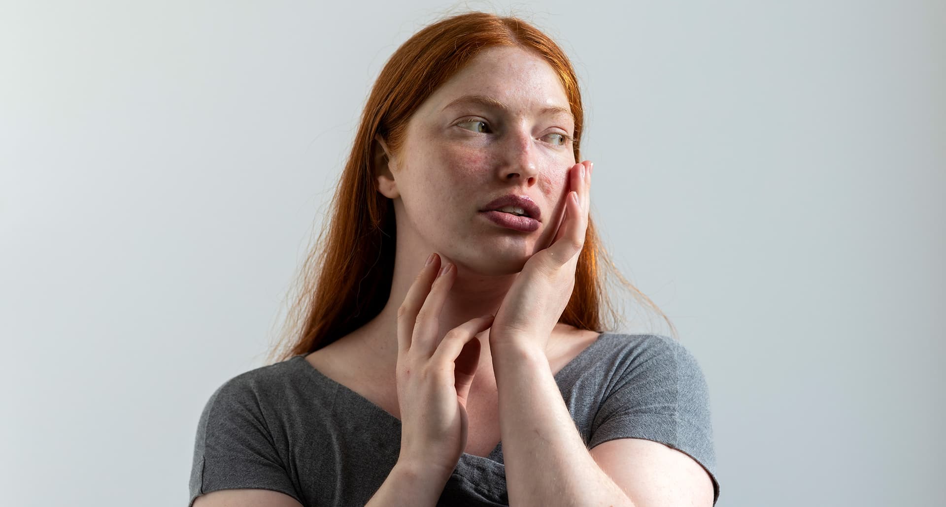 Woman with red hair touches her face, considering the Caveman Method