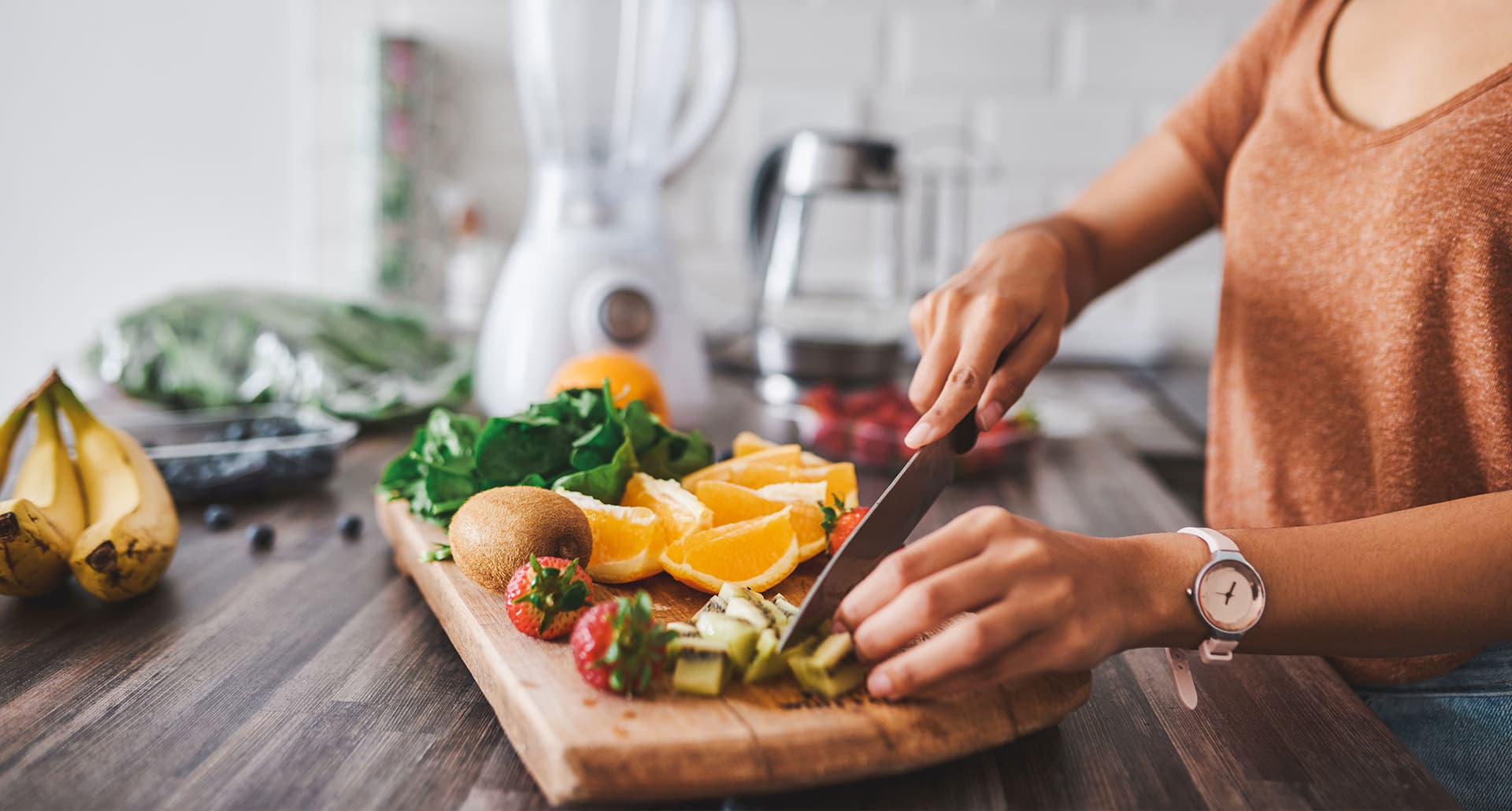 low sugar fruits: two hands cutting fruit on a wooden cutting board