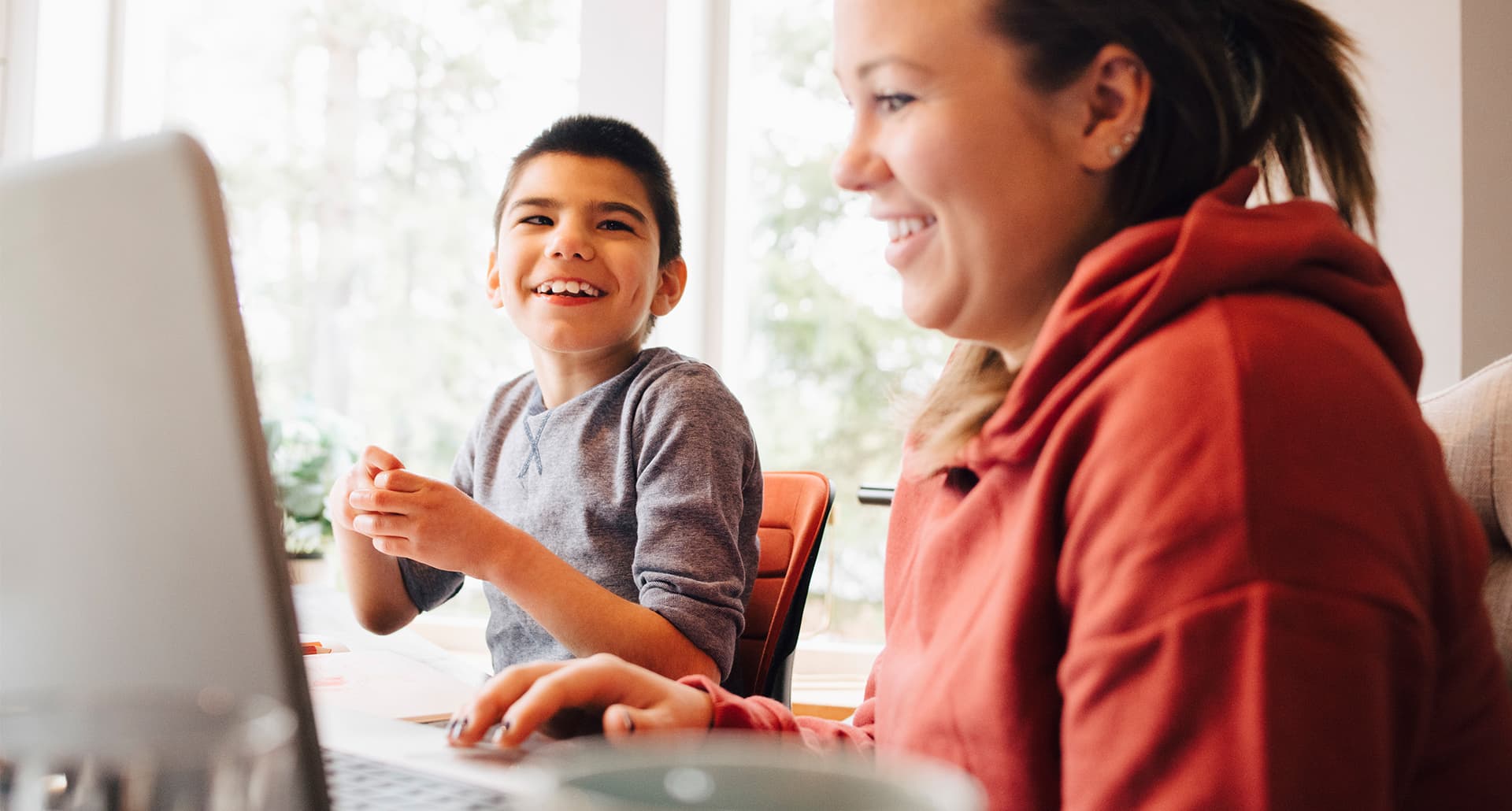 What Happens When Kids with Autism Grow Up: Mother using laptop while sitting with happy autistic son in living room at home