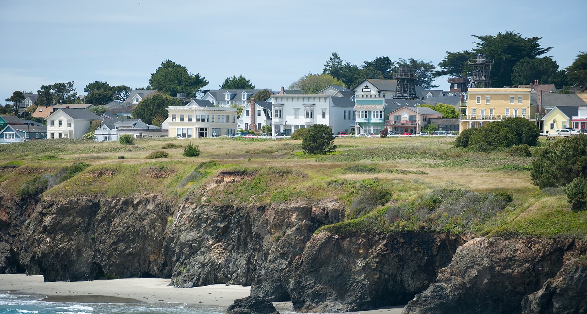 how-to-spend-a-weekend-in-mendocino: houses in mendocino, california set upon a hill overlooking the water.