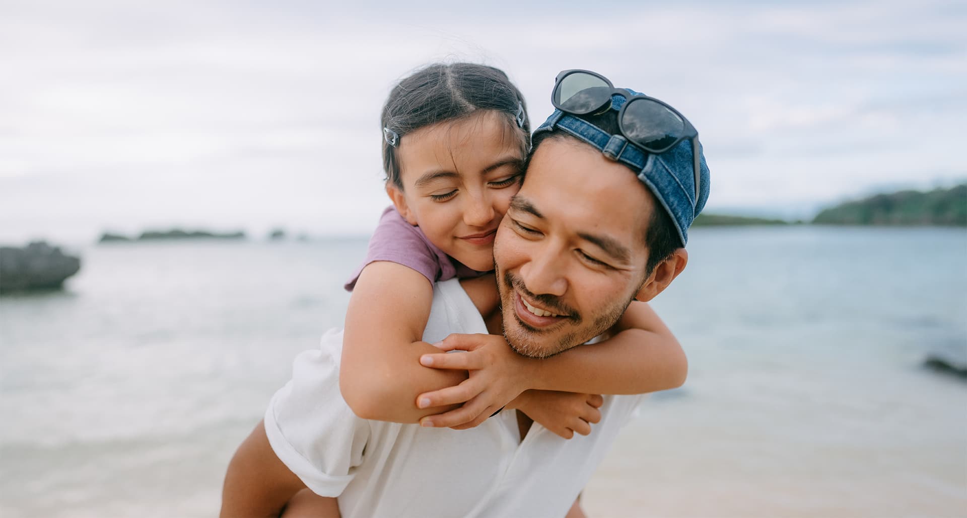 father's day quotes: asian dad piggy backing his daughter on the beach