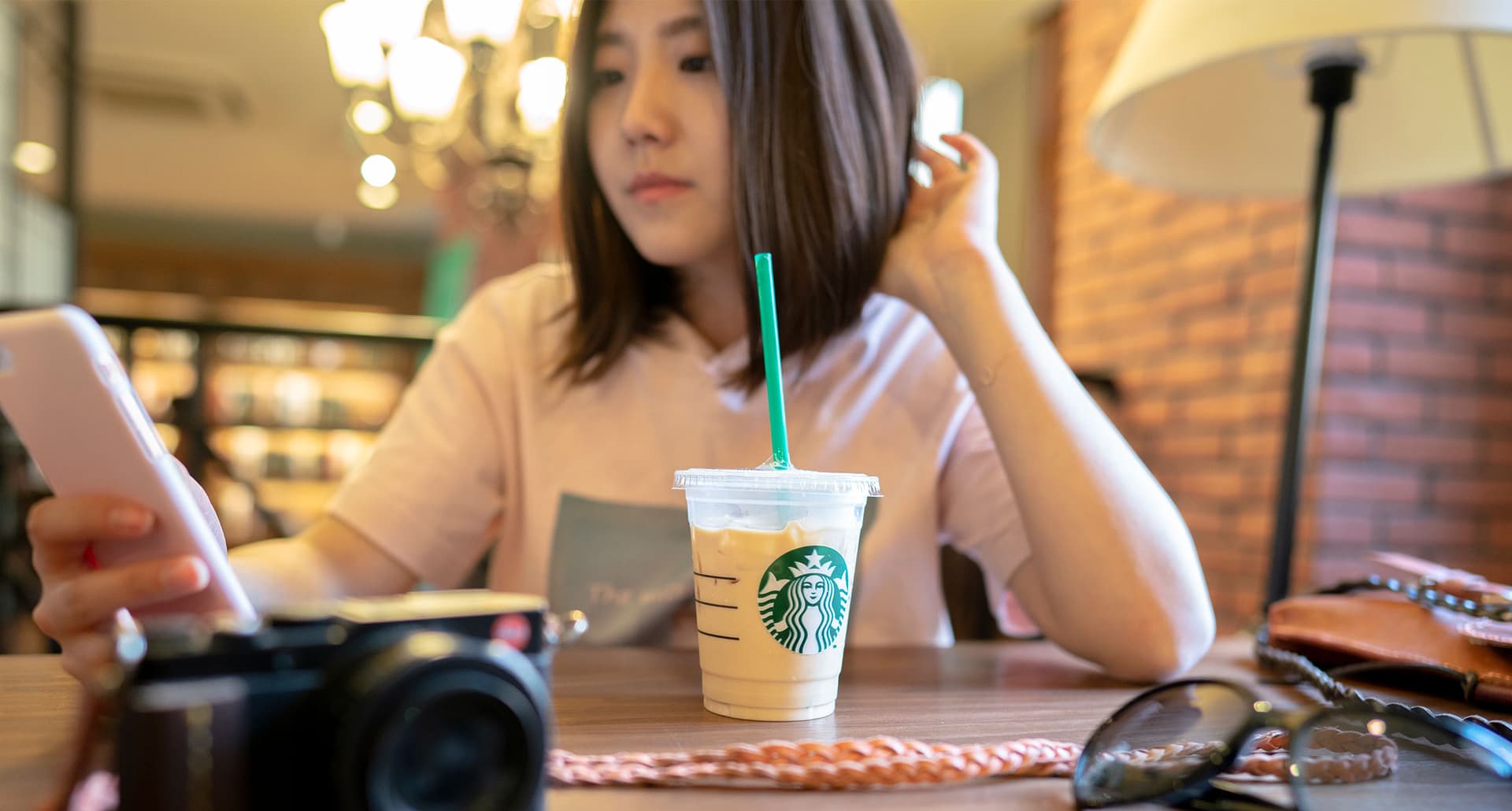 starbucks drinks for kids: young girl drinking an iced starbucks drink at a cafe