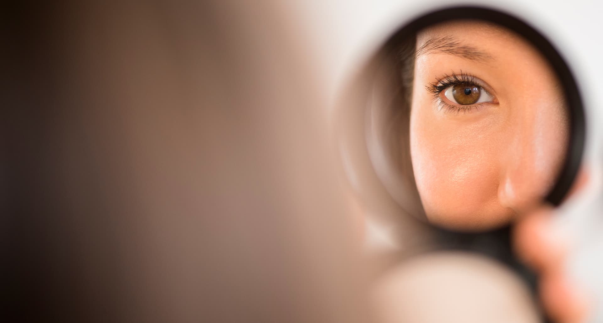 what is ozempic face universal: a woman looking into a compact mirror